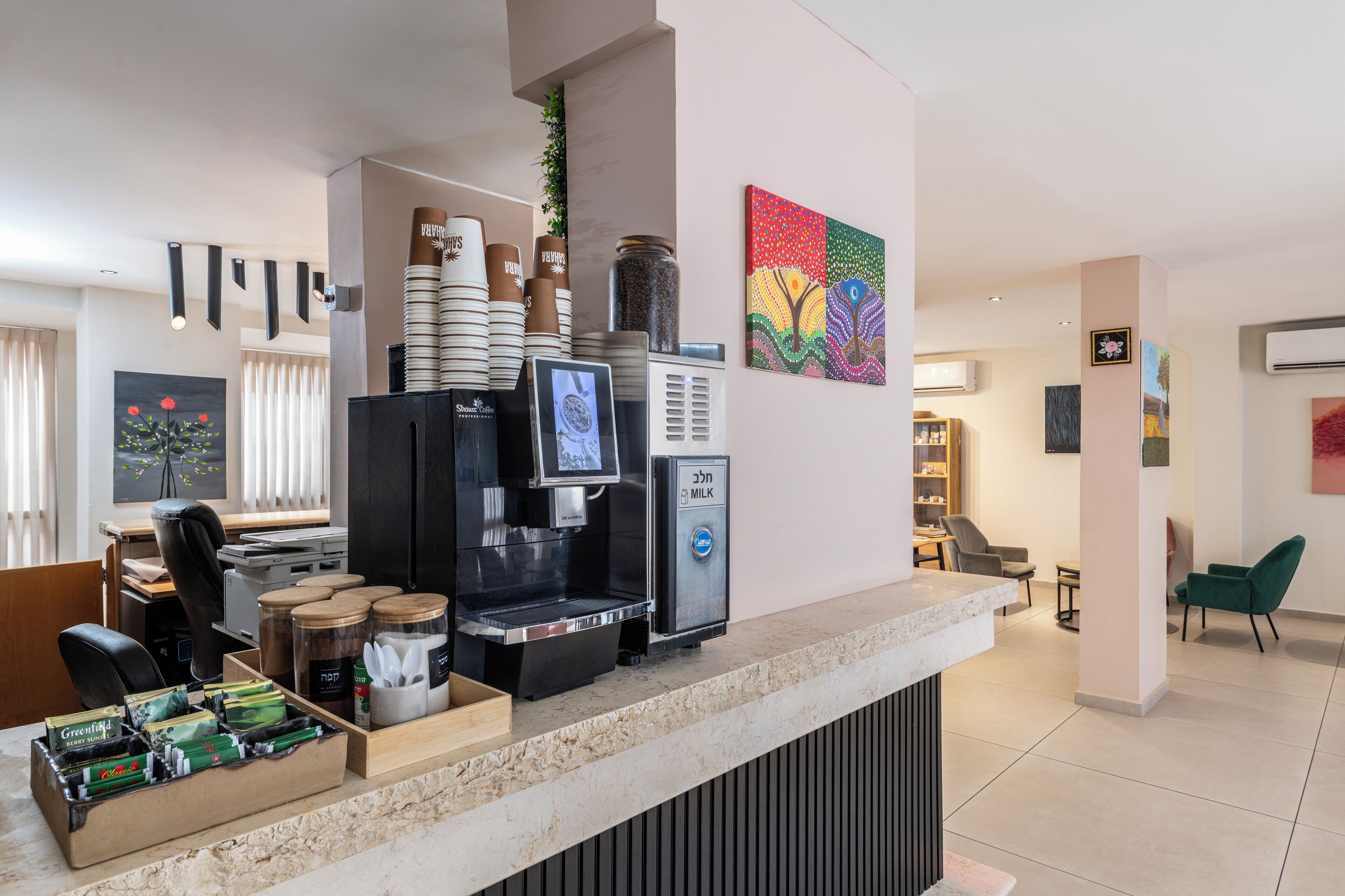 Een moderne koffiehoek met een koffieapparaat, melkdispenser en verschillende koffiekops.