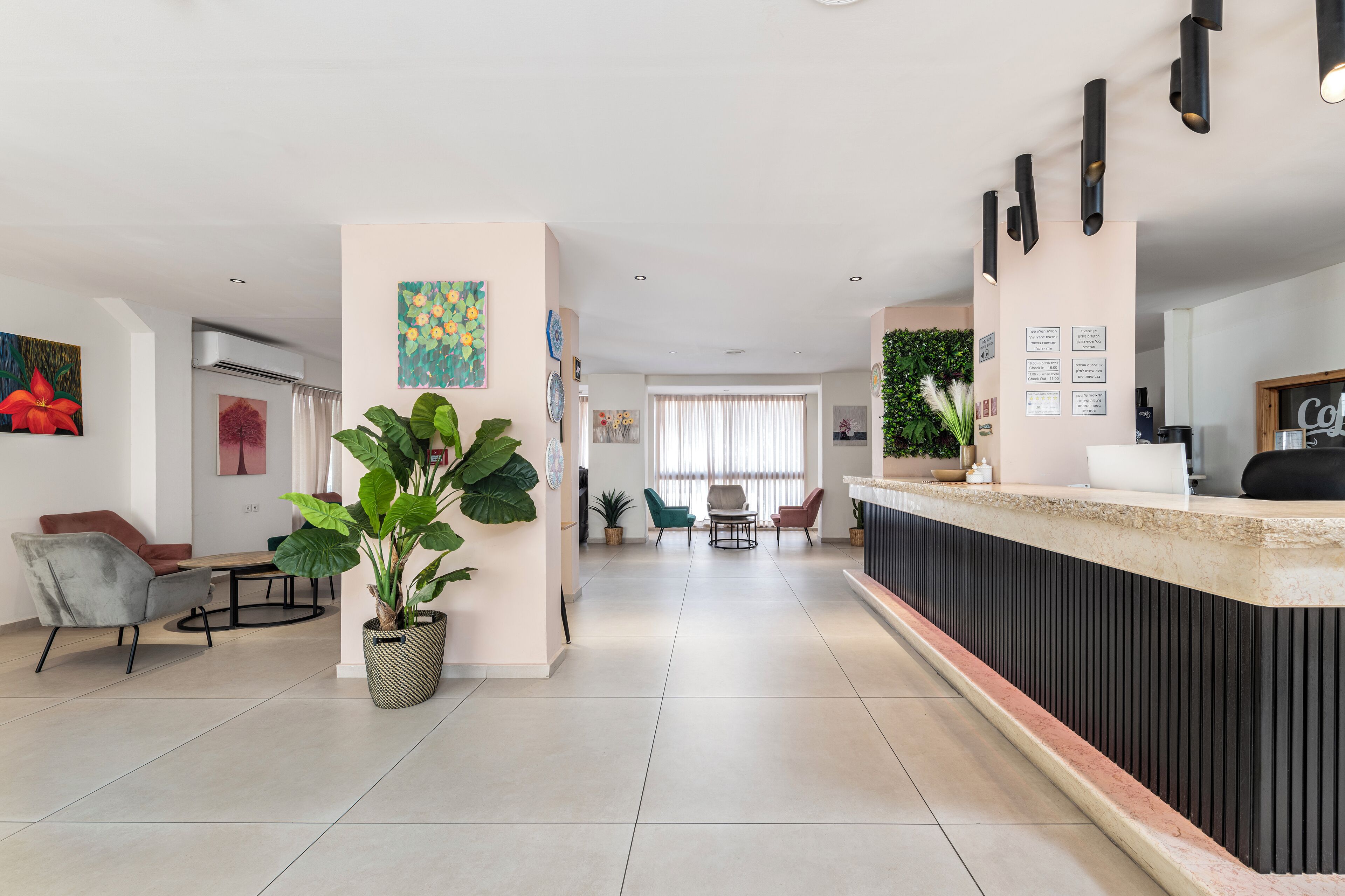 Un moderno vestíbulo de hotel con una recepción, área de descanso y grandes plantas en macetas.