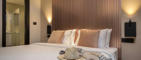 A hotel room with a large bed, a mirror, and a wall-mounted light fixture.