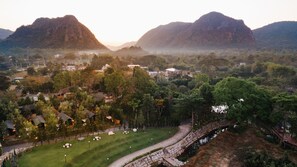 Escape to a serene park surrounded by majestic mountains and a rustic stone bridge.