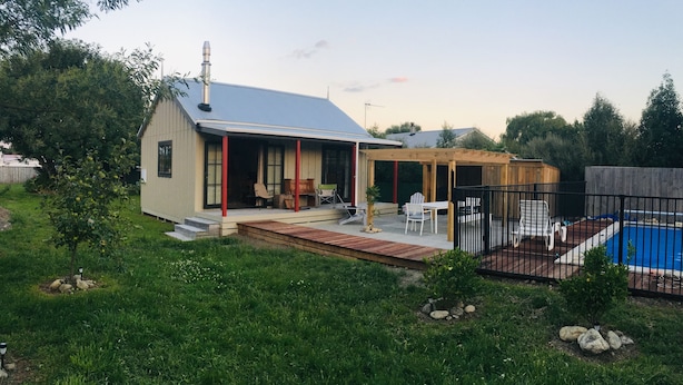 A house with a covered patio, a swimming pool, and a fenced backyard. - Prvt cottage + cabin + pool on quarter acre section (wood burner, pet friendly) (Greytown)