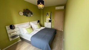 A bedroom with a bed, bedside tables, a dresser, a mirror, and a door.