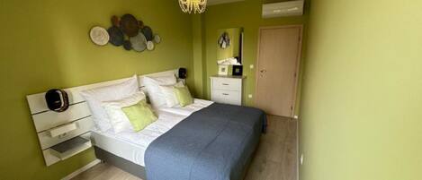 A bedroom with a bed, bedside tables, a dresser, a mirror, and a door.