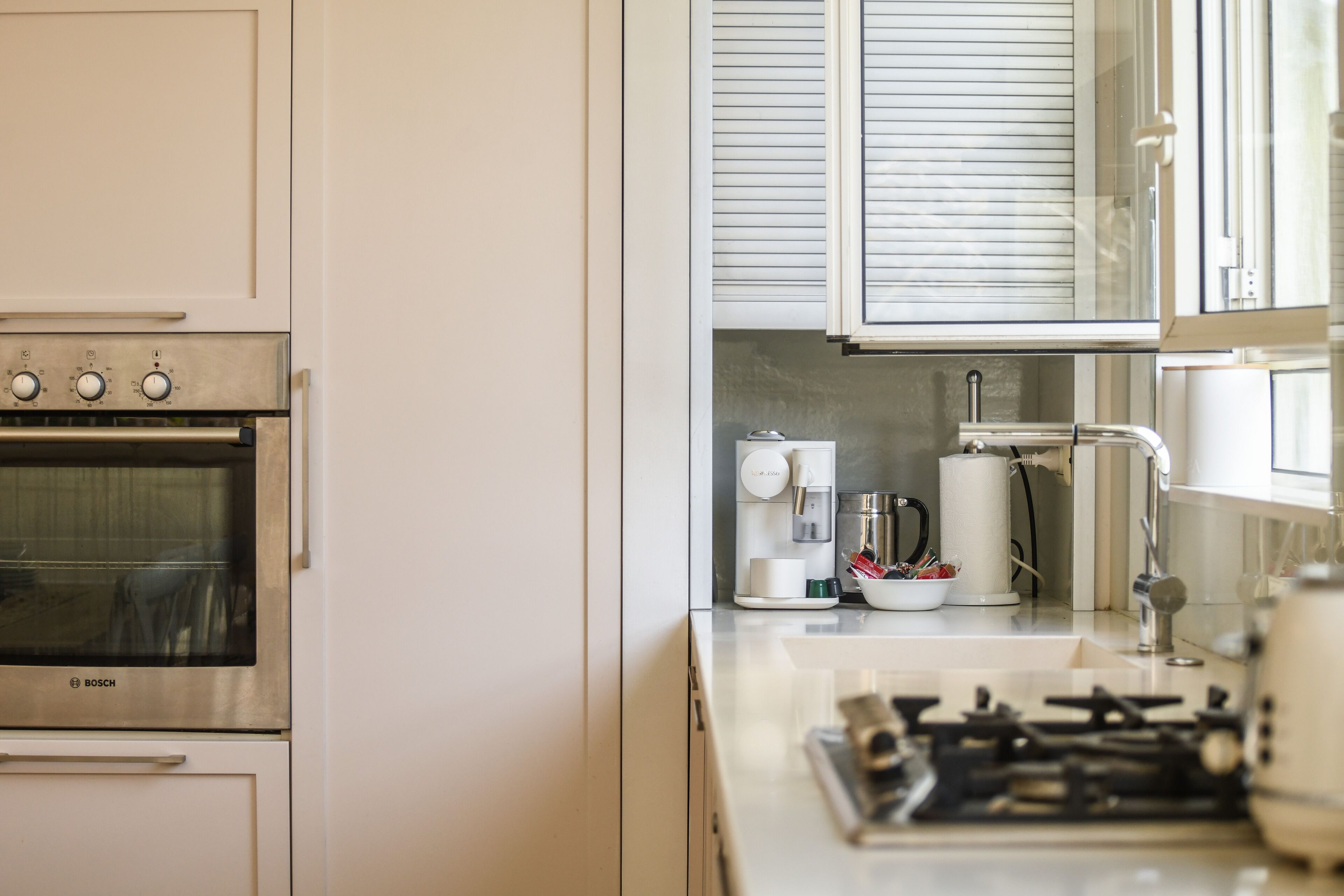 A kitchen with a Bosch oven, a coffee maker, and a gas stove.