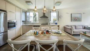 Eine moderne Küche mit weißen Schränken, einem Holztisch und Pendelleuchten.