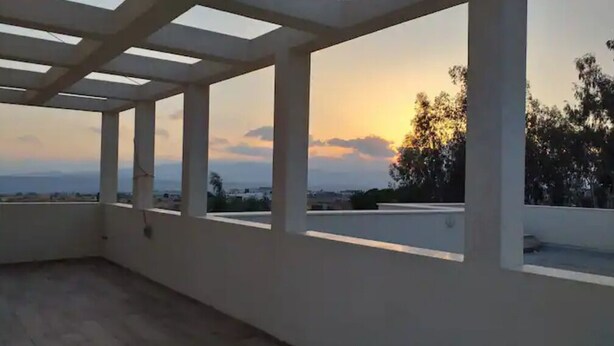 Eine Dachterrasse mit Blick auf den Sonnenuntergang und die ferne Landschaft.