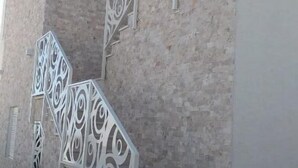 Eine Treppe mit aufwendig gestalteten Metallgeländern an einer Steinwand.