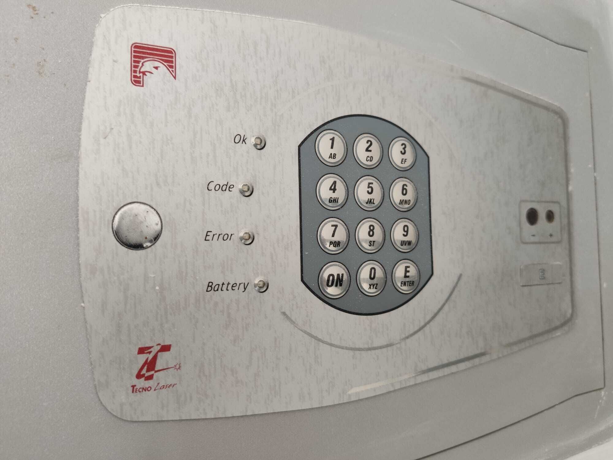Painel de controle com botões rotulados 'OK', 'Código', 'Erro' e 'Bateria', juntamente com um teclado numérico.