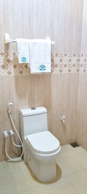 A bathroom with a toilet, a shower, and a towel rack.