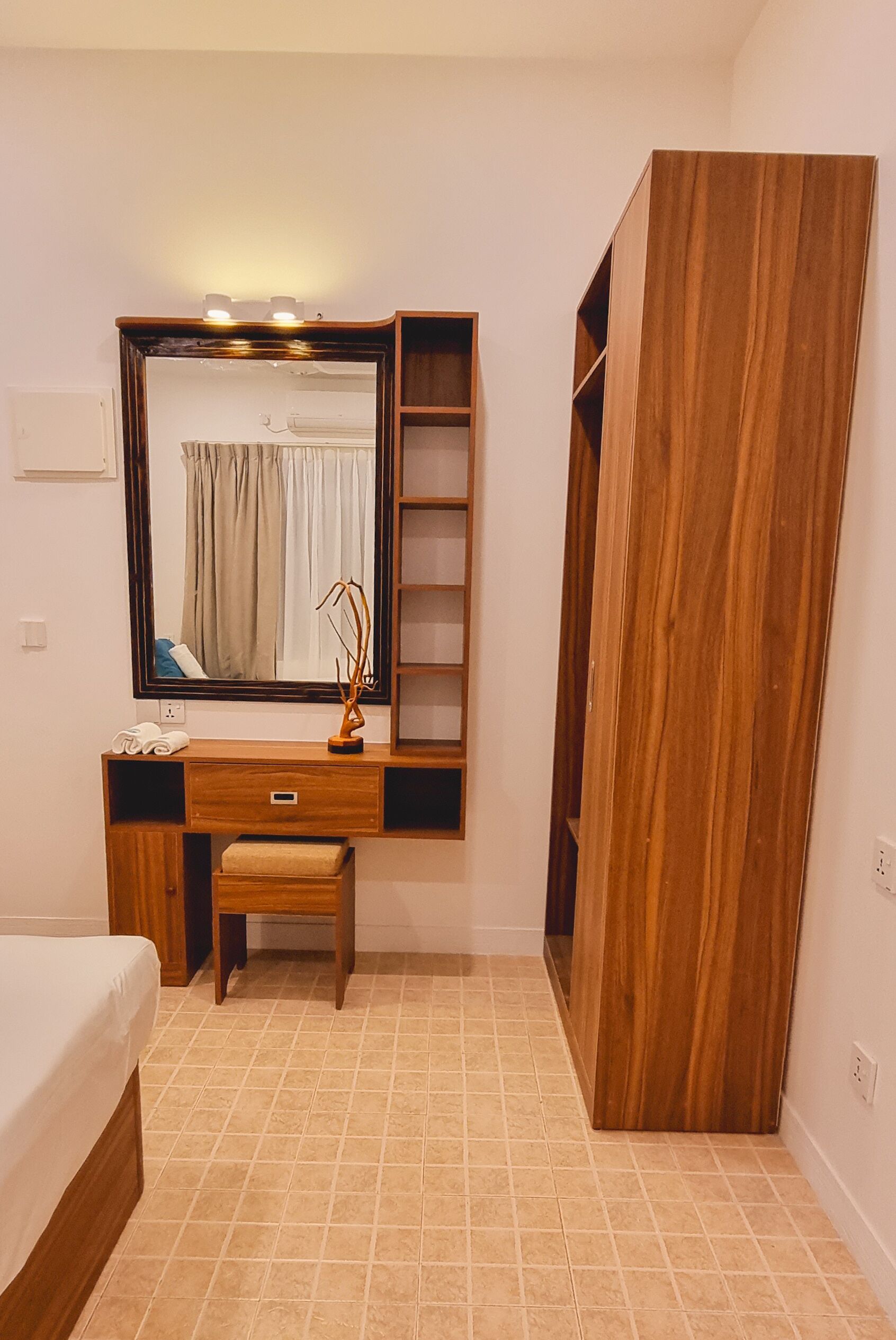 Une chambre à coucher avec une coiffeuse en bois, un miroir, un lit et une armoire.