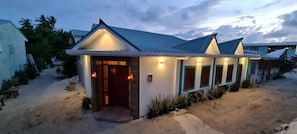 A beachfront house with a tiled roof, a front porch, and a small garden area.