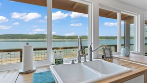 A kitchen with a large sink, wooden countertop, and a view of a lake. - Keys on the Canal - Stunning Beachfront Bungalow! (Belfair)
