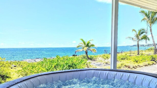 Een bubbelbad met uitzicht op de oceaan en palmbomen.