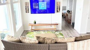 Een woonkamer met een grote flatscreen televisie, een gebogen bank en een houten salontafel.