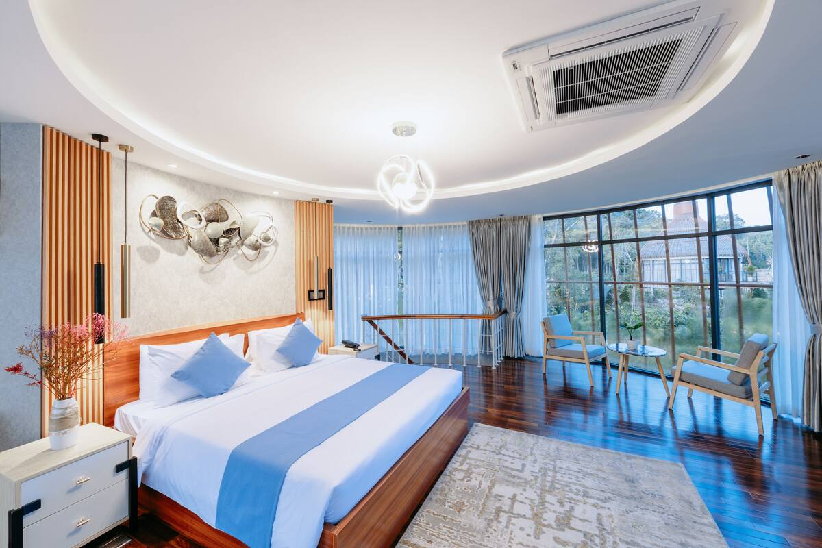 A modern hotel room with a large bed, a seating area, and a view of the outdoors.