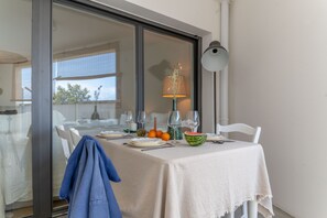 A dining table set with a white tablecloth, a vase with dried flowers, a bowl of fruit, and a lamp. - Bel Appartement Lumineux à Biarritz (Biarritz)