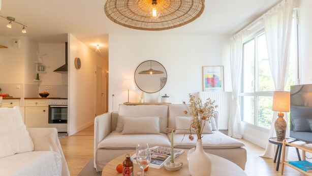 Una sala de estar moderna con una mesa redonda, un sofá, un televisor y un comedor con mesa y sillas.