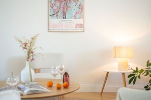 A dining area with a round table, a vase with dried flowers, a bottle, and a lamp on a side table. - Bel Appartement Lumineux à Biarritz (Biarritz)