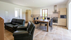 A modern kitchen with a dining area, a sofa, and a small table with chairs.