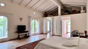 A spacious bedroom with a large bed, a television, and a view of the outdoors through a window. - Propriété de Charme à Bonifacio (Bonifacio)