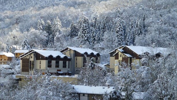 Un ensemble de bâtiments de style chalet, entourés d’arbres couverts de neige.