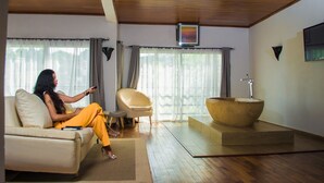 Una sala de estar moderna con un sofá, una silla, un lavabo de madera grande y una ventana con cortinas.