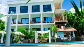 Un hotel de varios pisos con piscina, zona de estar al aire libre y terraza en la azotea.