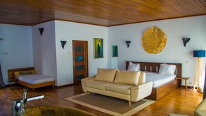 Un dormitorio con cama, sofá, piso de madera y un gran adorno en la pared.