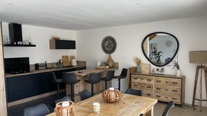 A modern kitchen with a dining area, featuring a wooden table, black chairs, and a large mirror.