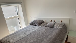 A bedroom with a bed, pillows, a nightstand, and a window.