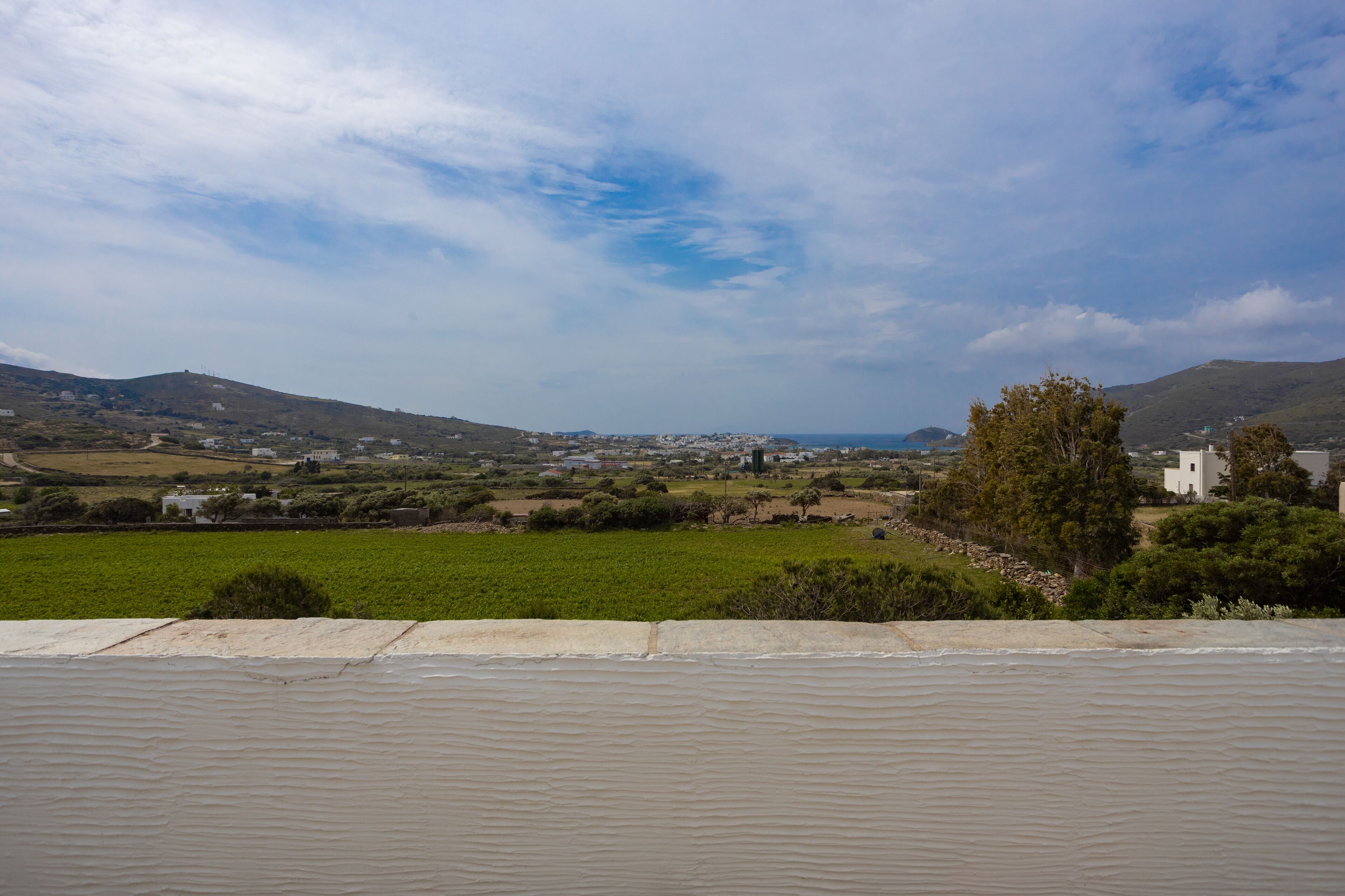 Eine Küstenlandschaft mit Blick auf einen Strand, eine kleine Stadt und sanfte Hügel in der Ferne.