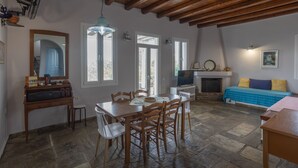 A dining area with a wooden table and chairs, a mirror, and a television. - Cycladic Blue Andros (Γαύριο)