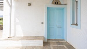 A white building with a blue door and a small window. - Cycladic Blue Andros (Γαύριο)