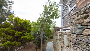 A stone wall with a wooden fence, a stone pathway, and trees. - Cycladic Blue Andros (Γαύριο)