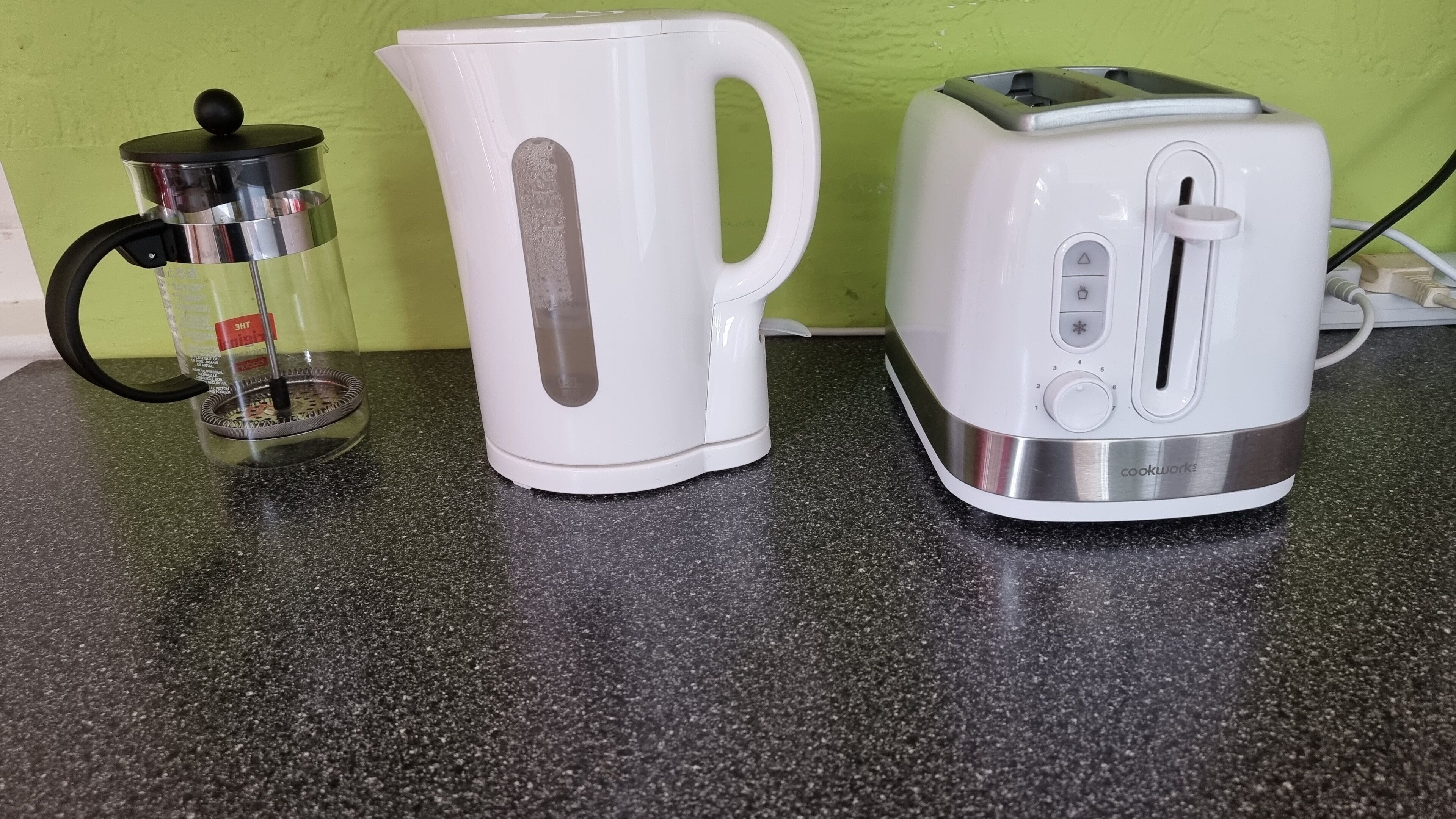 Una encimera de cocina con una cafetera, un hervidor y un tostador.