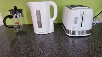 Una encimera de cocina con una cafetera, un hervidor y un tostador.