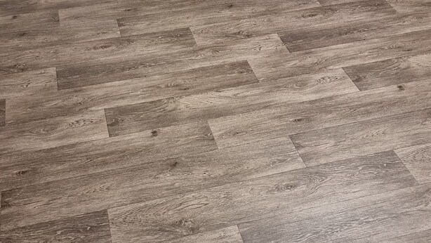 Un comedor con una mesa y sillas de madera, un felpudo y un suelo con patrón de espiga.