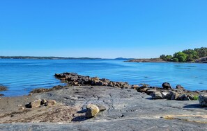 Una costa rocosa con agua tranquila y tierra a lo lejos.