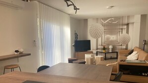 Una sala de estar moderna con una mesa de comedor de madera, un televisor de pantalla plana y un sofá.
