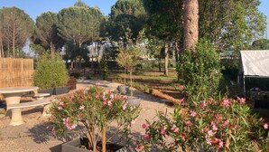 Un jardín con valla de madera, una mesa y plantas en macetas.