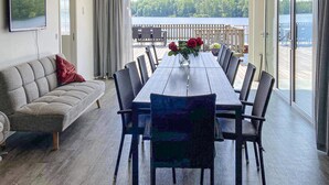 A dining area with a table and chairs, a sofa, a TV, and a view of a lake. - Stunning home in Tingsryd with WiFi (Tingsryd)