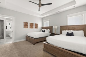 Une chambre avec deux lits, un ventilateur de plafond, un dressing et une salle de bain.