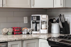 Une cuisine équipée d’une machine à café, d’un moulin à café, d’une tasse à café et d’un bloc à couteaux.