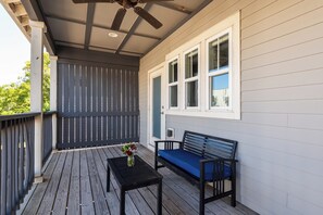 Une véranda couverte avec un ventilateur de plafond, un banc et une table.