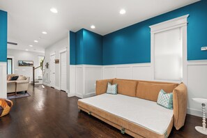 Un salon moderne avec un canapé, un parquet et un mur d’accent bleu.