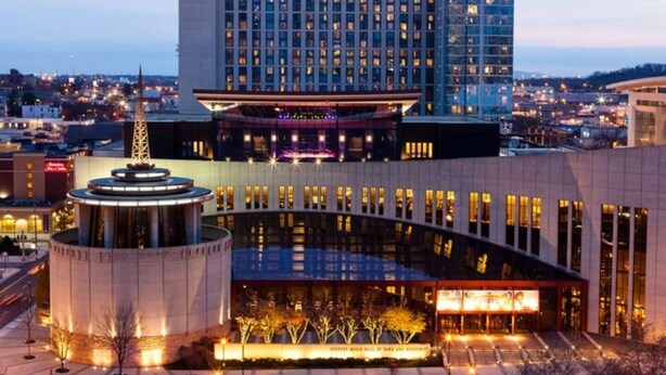Een hotel met een modern design, met een opvallend, rond gebouw op de voorgrond en een hoog hotel in de verte.