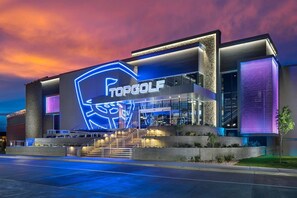 Ein modernes Gebäude mit einem großen, beleuchteten Logo und dem Schriftzug "TOPGOLF" an der Fassade.