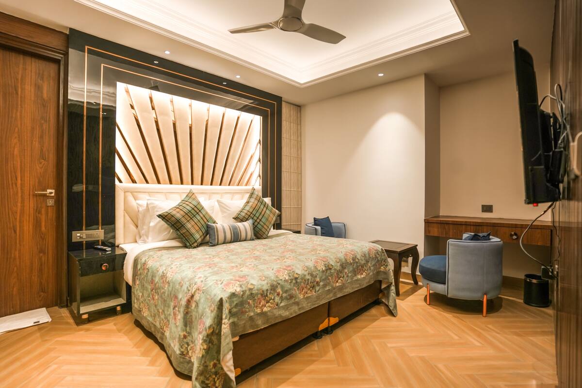 A modern bedroom with a large bed, a desk, a chair, and a ceiling fan.