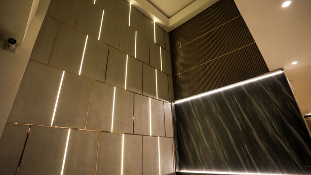 A modern interior with a geometric wall design and recessed lighting. - Atithi House (Greater Noida)