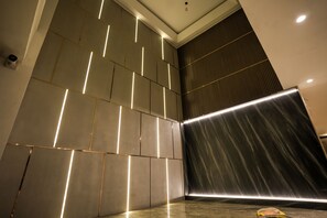 A modern interior with a geometric wall design and recessed lighting. - Atithi House (Greater Noida)